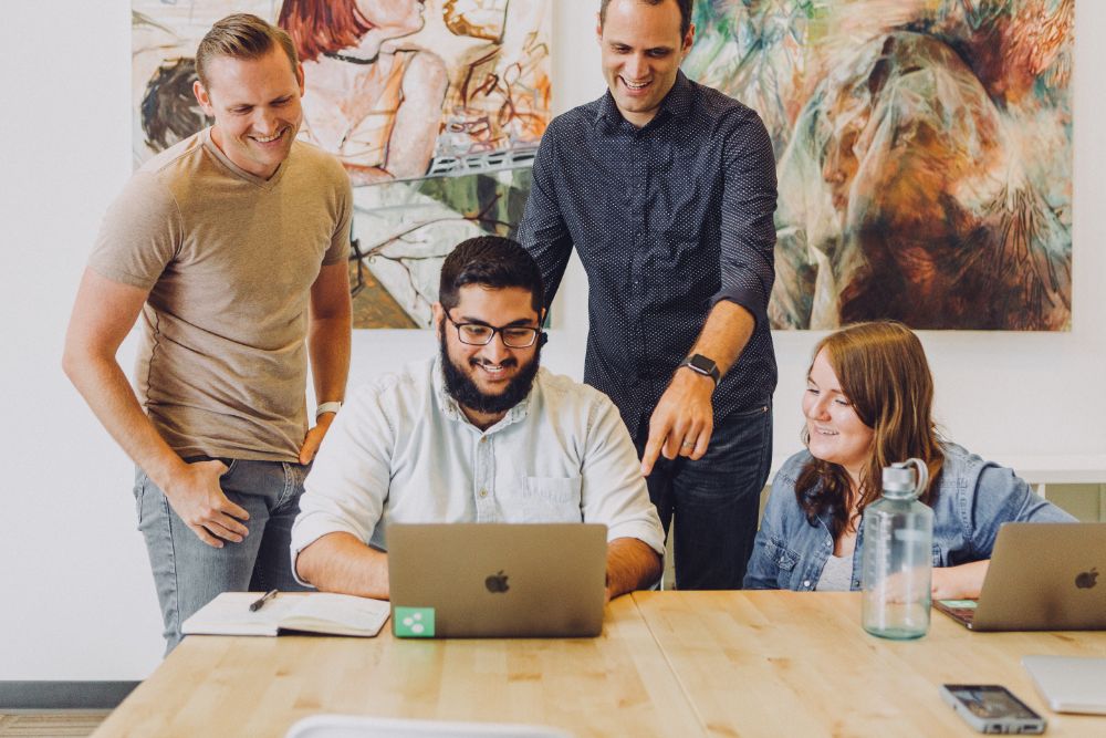 four people staring at a computer